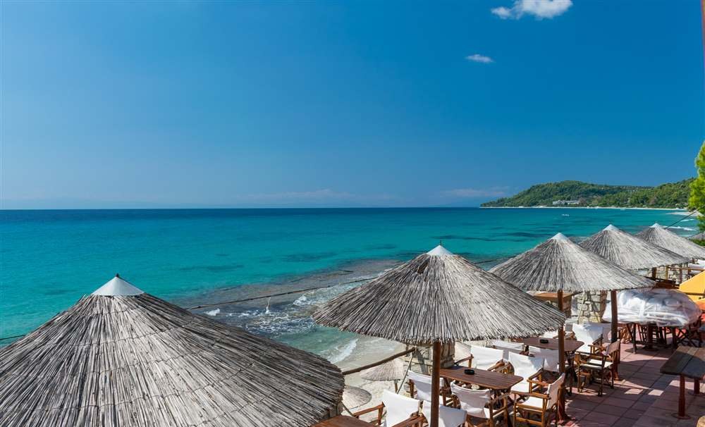 Kudu Beach Bar seen from the sea — umbrellas, stone terraces and gardens above the beach