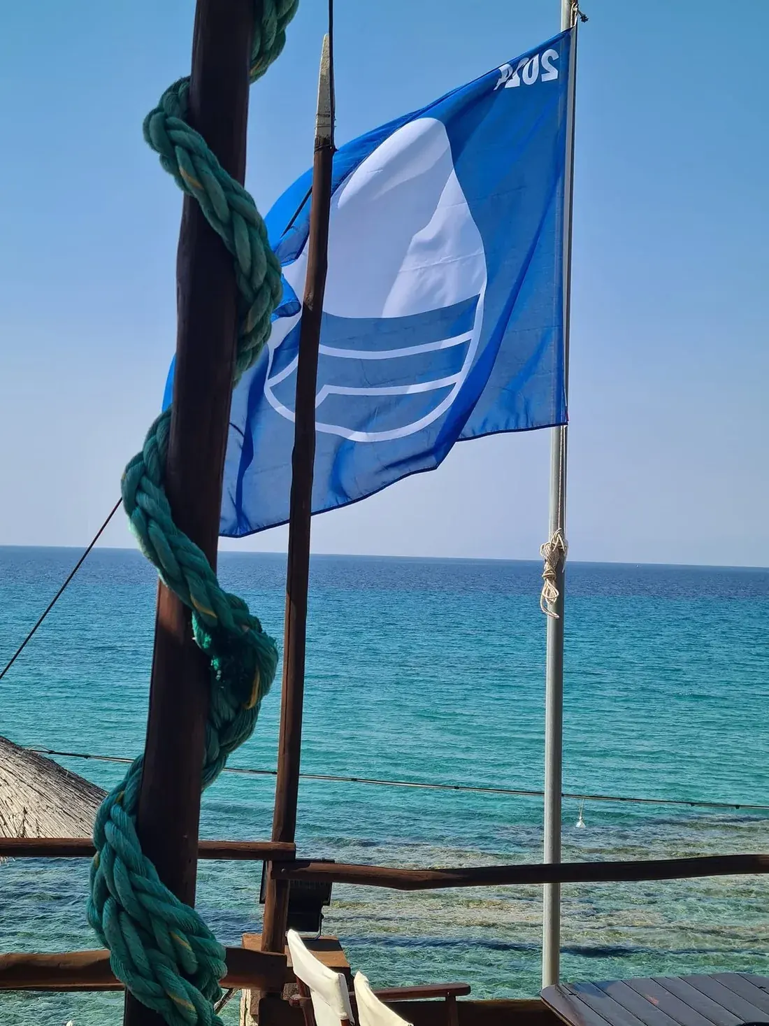 Blue Flag flying over the clear turquoise sea at Kudu's beach