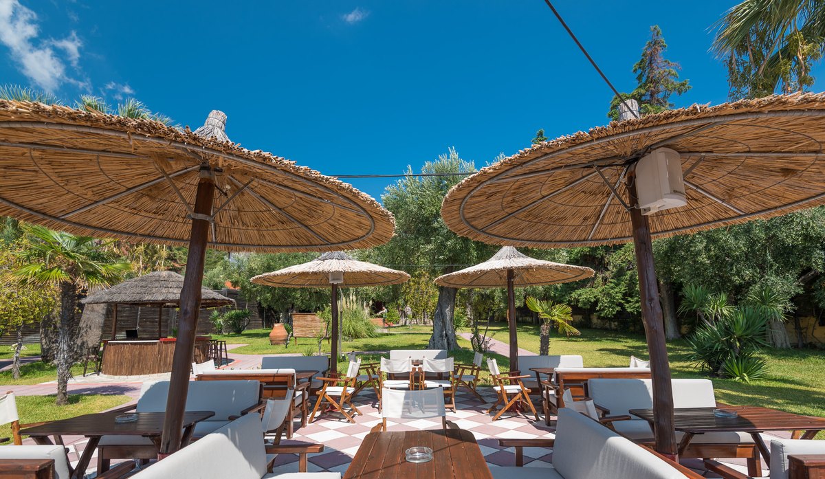 White cushioned loungers under straw umbrellas in Kudu's garden